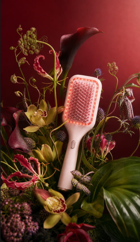 Vibrating Scalp Serum Comb with LED light therapy among flowers